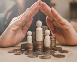 Family insurance plan protect. Help medicine protection. Father mother children insurance. A hand is protecting three small figurines and a pile of coins. Concept of financial security and protection.